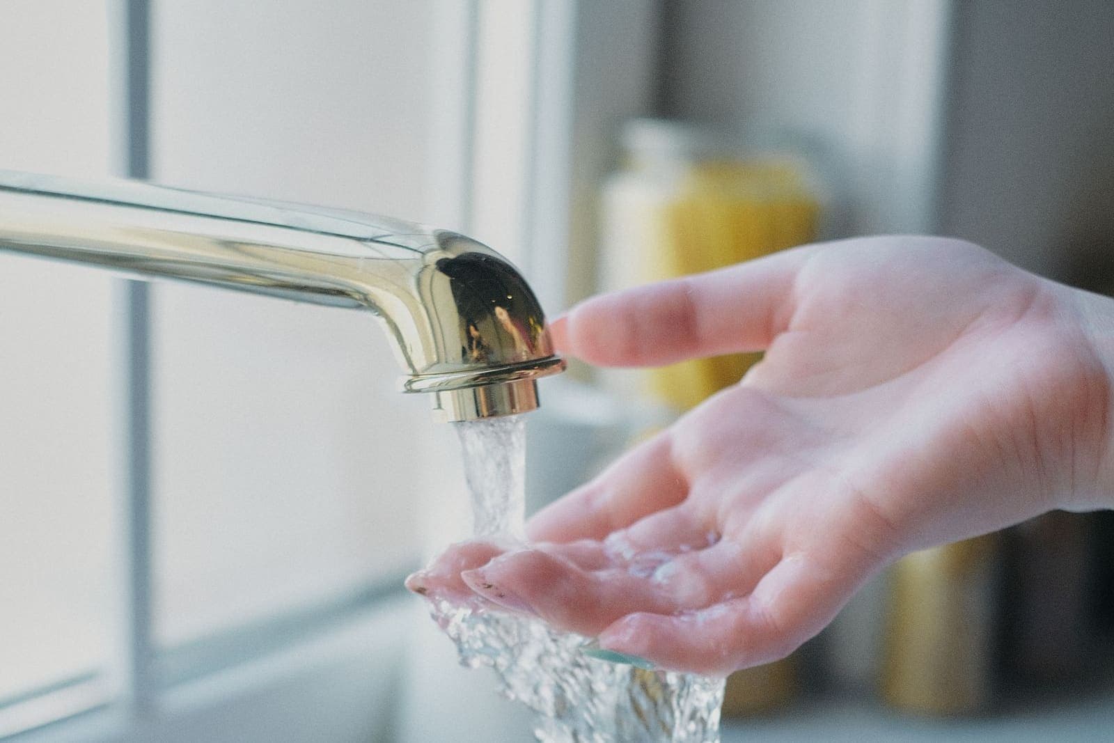 Hand under water running from a kitchen tap