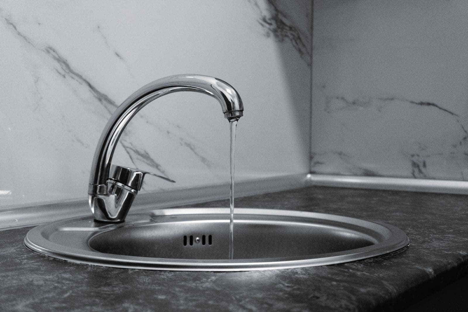 Chrome kitchen faucet running into a sink