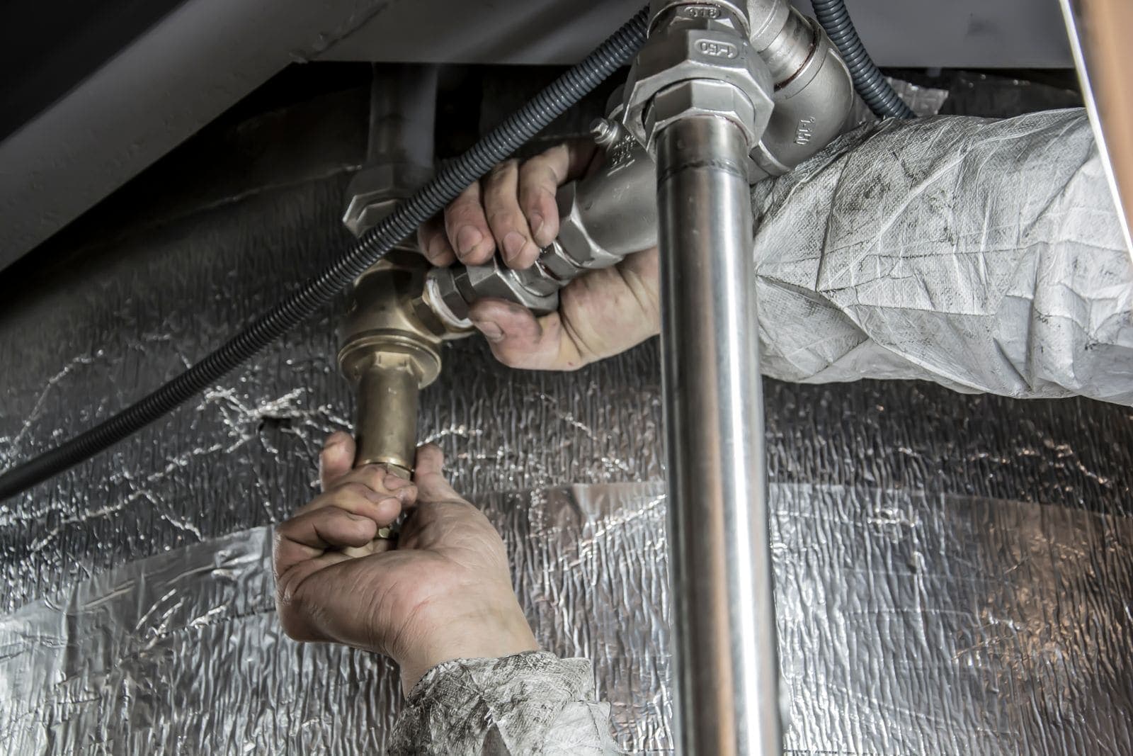 Plumber tightening a pipe fitting by hand