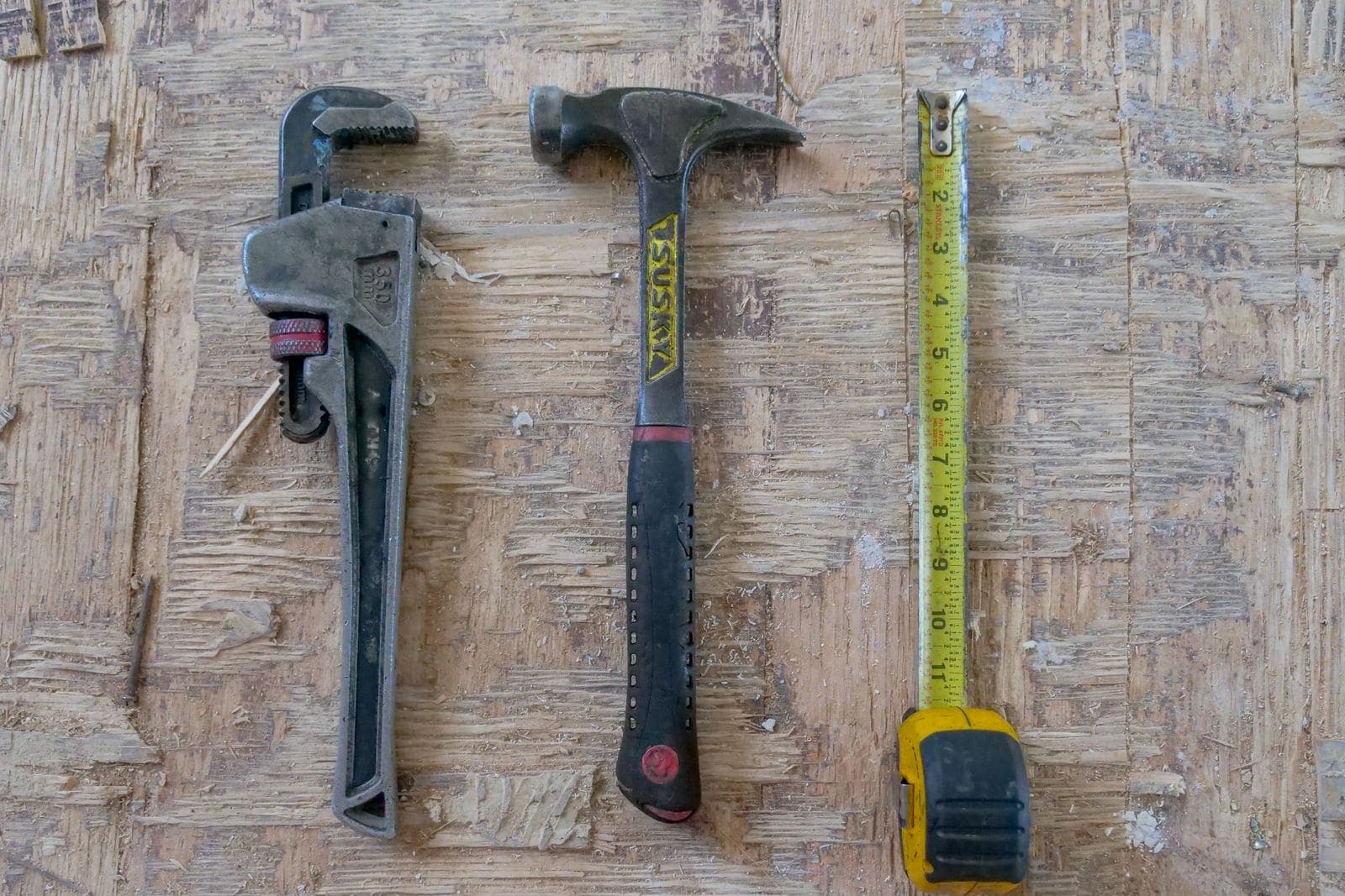Pipe wrench, hammer and tape measure on a workbench